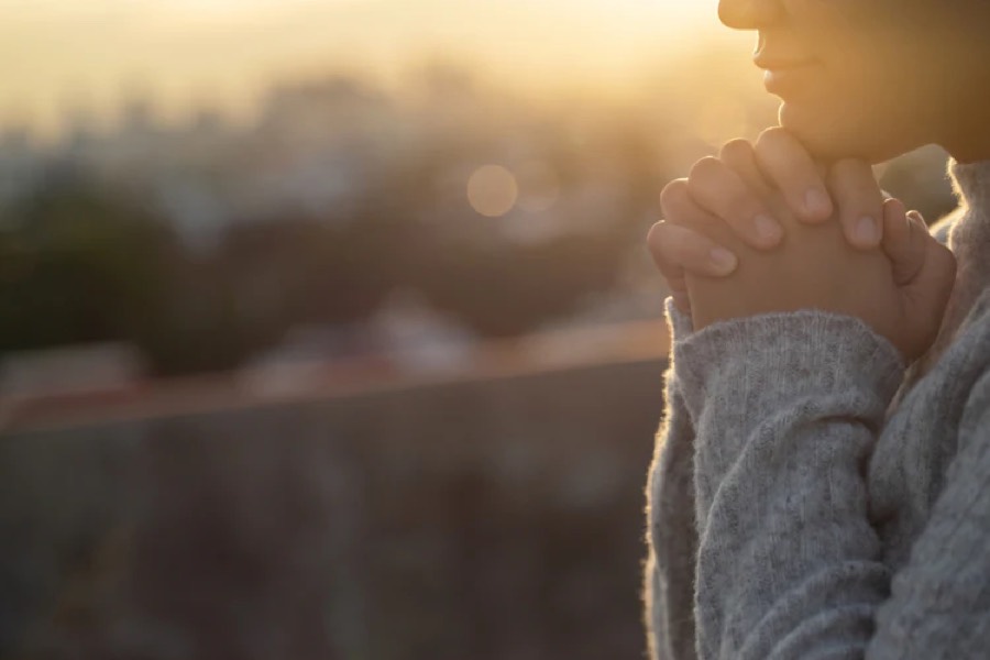 Person praying with folded hands